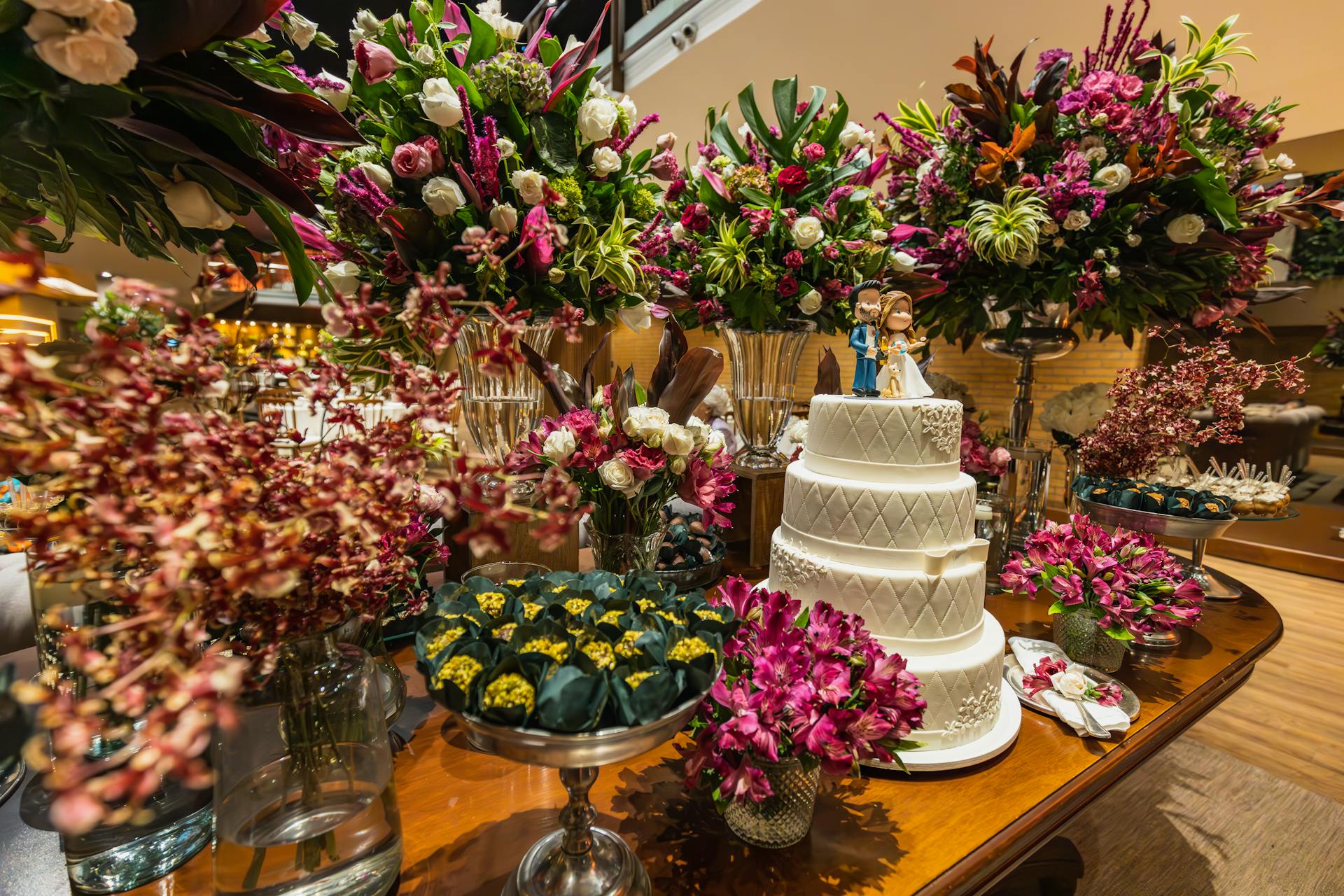 A beautifully decorated wedding table featuring a white tiered cake and vibrant floral arrangements.