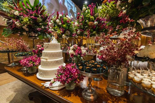 Free A beautifully decorated wedding cake table with vibrant floral bouquets, creating an elegant celebration ambiance. Stock Photo