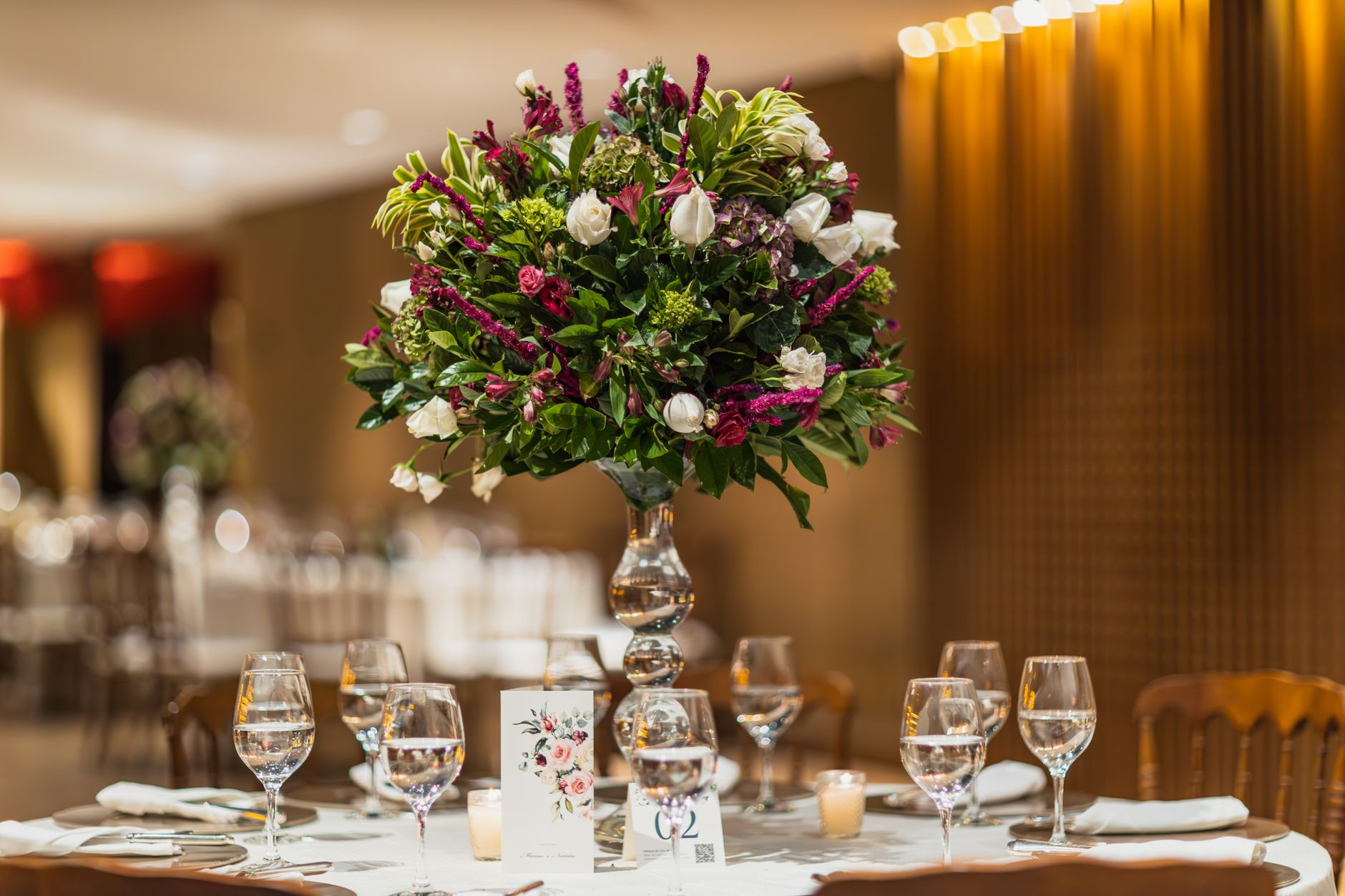 A beautifully arranged floral centerpiece adorns an elegantly set table in a luxurious restaurant space.