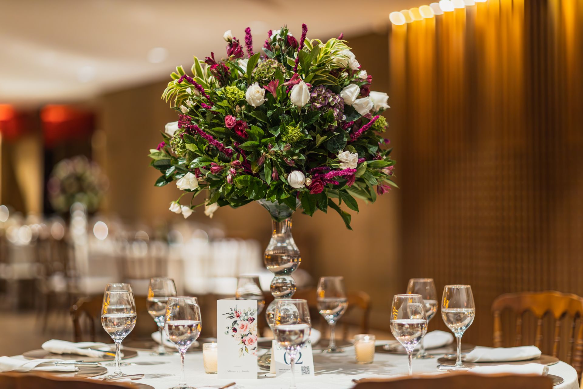 A beautifully arranged floral centerpiece adorns an elegantly set table in a luxurious restaurant space.