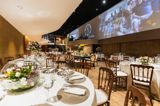 An elegant wedding reception setup with floral arrangements and elegant table settings in a spacious venue.