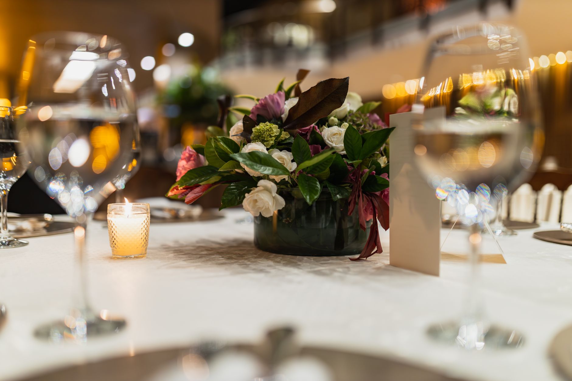 A beautifully arranged table with floral centerpiece and candlelit ambiance at a wedding reception.