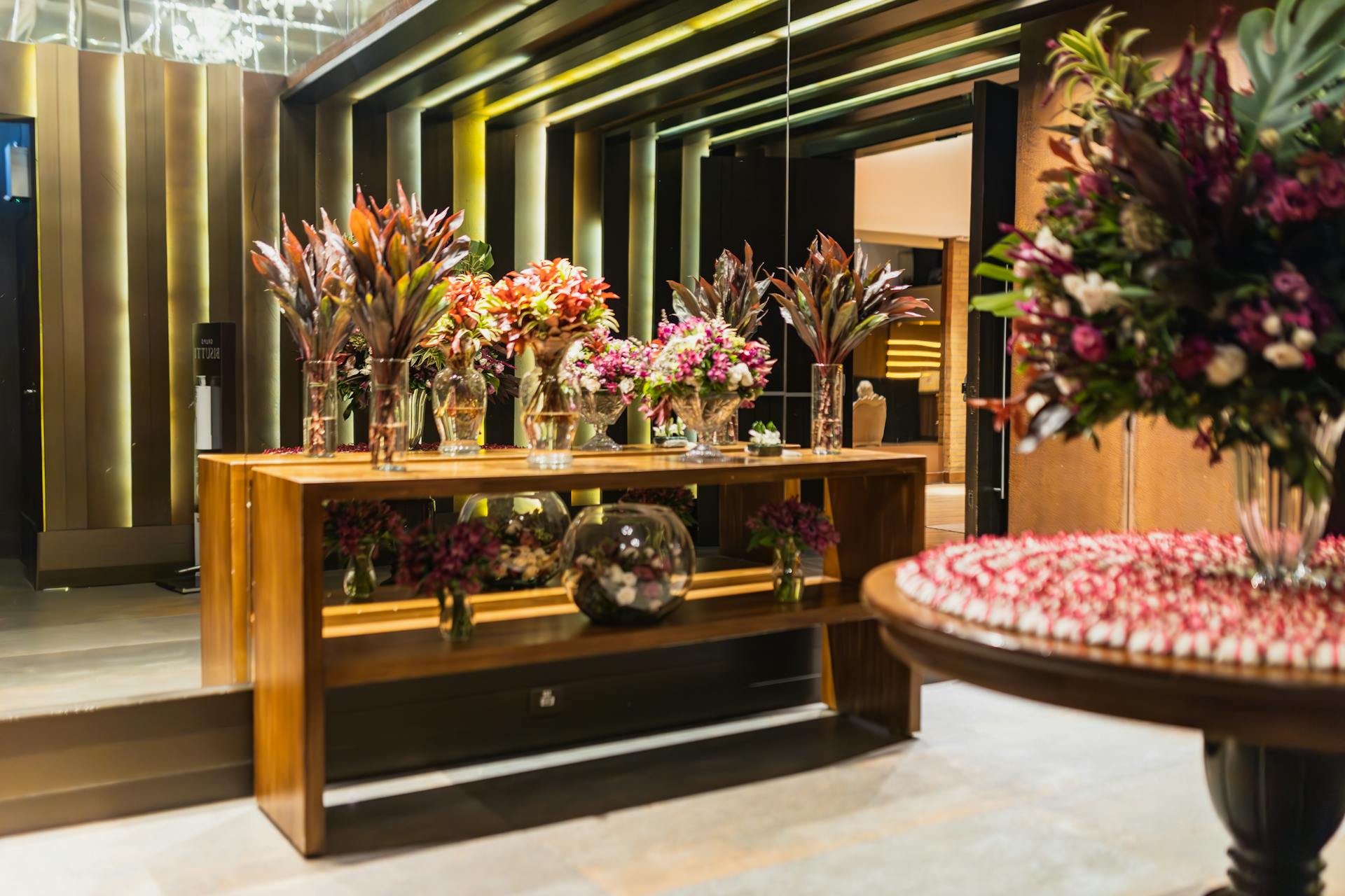 Luxurious hotel lobby features vibrant floral displays on wooden tables, enhancing the elegant interior design.