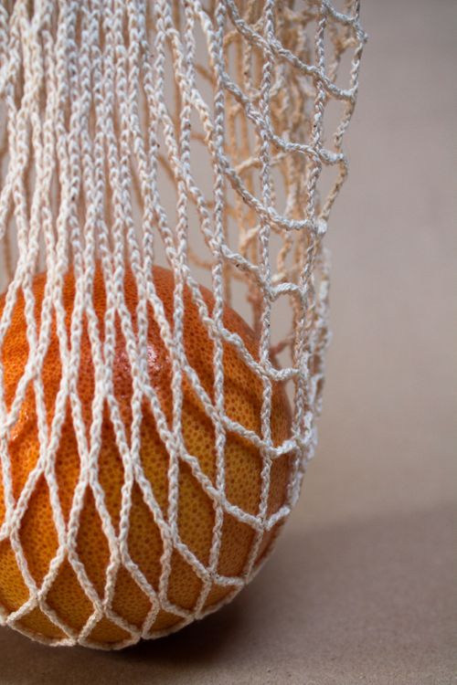 Free Close-up of a grapefruit in a reusable net bag on a soft background. Stock Photo