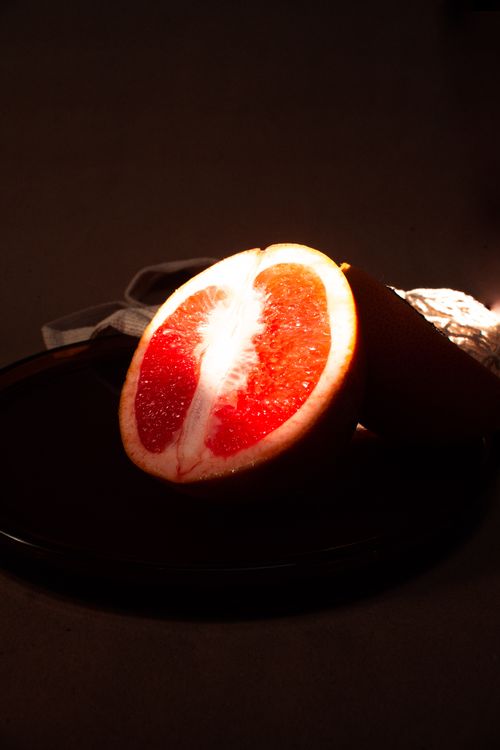 Free Close-up of a grapefruit half on a dark background highlighting its fresh, juicy texture. Stock Photo