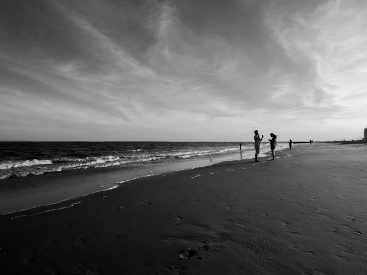 People Walking On Beach On Sunset