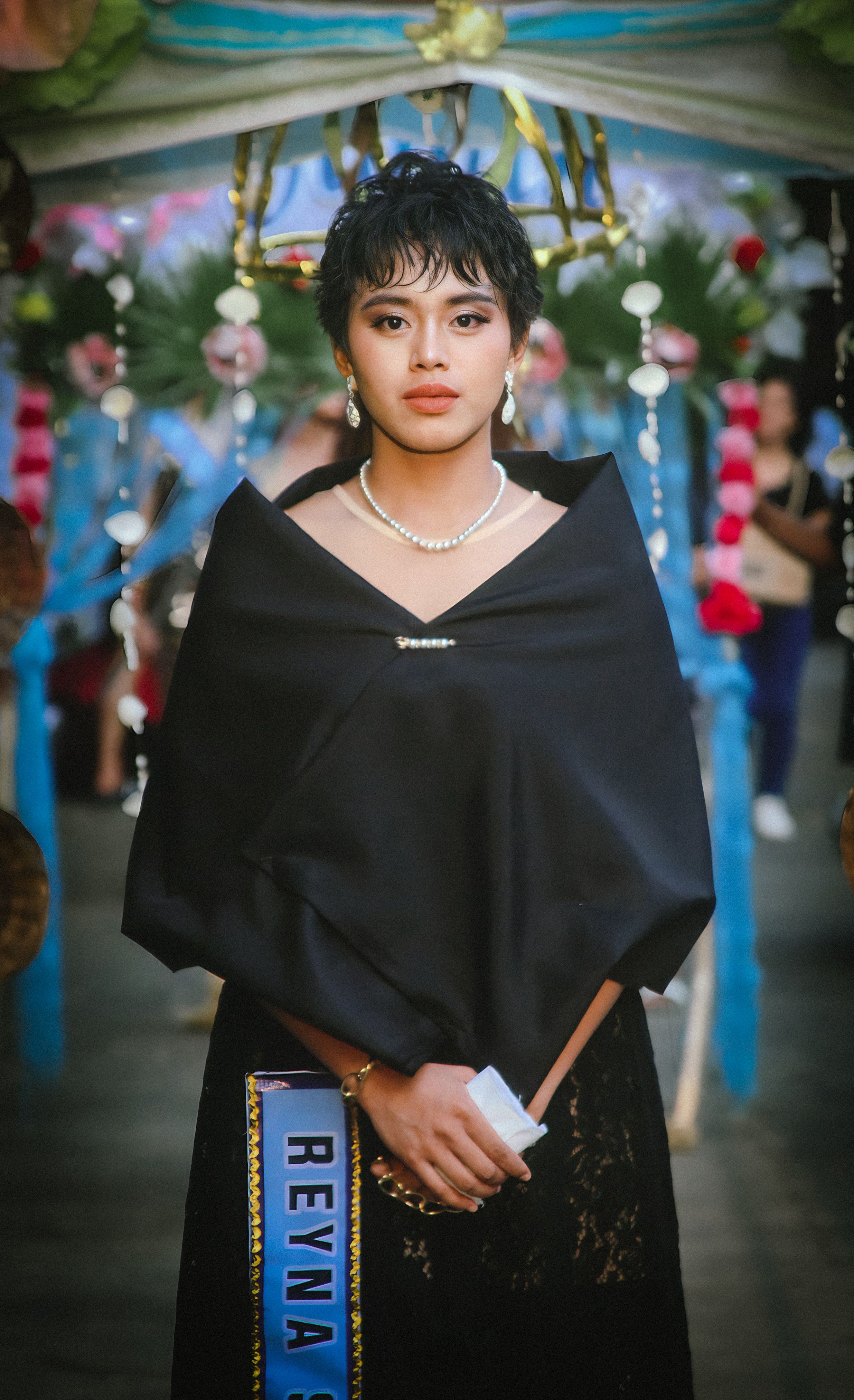 Young woman in traditional clothing with pearls at a cultural event.