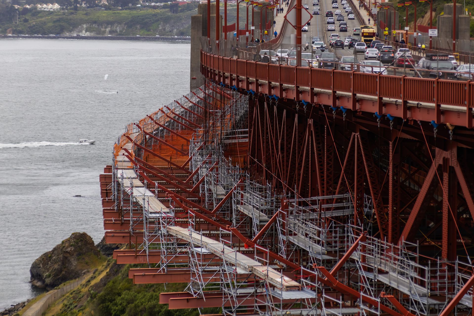 Golden Gate Bridge construction showing scaffolding and traffic over bay.