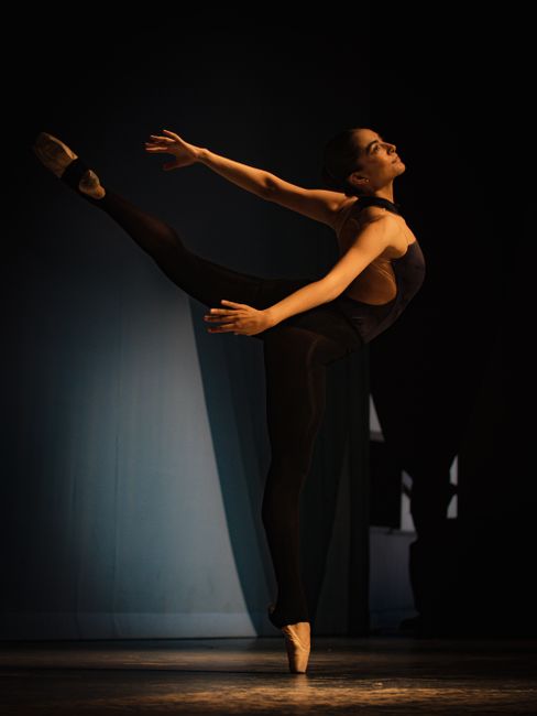 A graceful ballerina performing a ballet routine on stage, showcasing elegance and poise.