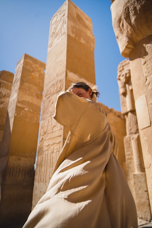 Low Angle Shot of a Woman in a Beige Coat at Luxor Temple, Luxor, Egypt 