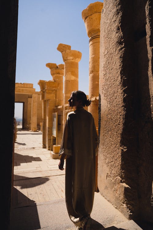 Back View of a Woman in a Beige Coat at Luxor Temple, Luxor, Egypt