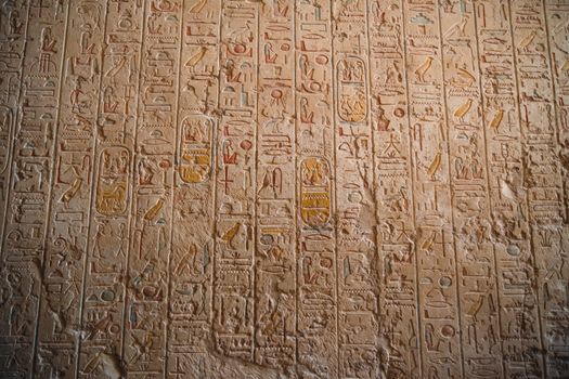Close-up of ancient Egyptian hieroglyphs carved on temple walls, showcasing historical art.