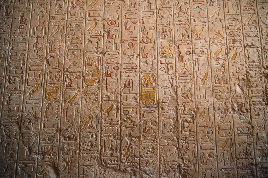 Close-up of ancient Egyptian hieroglyphs carved on temple walls, showcasing historical art.