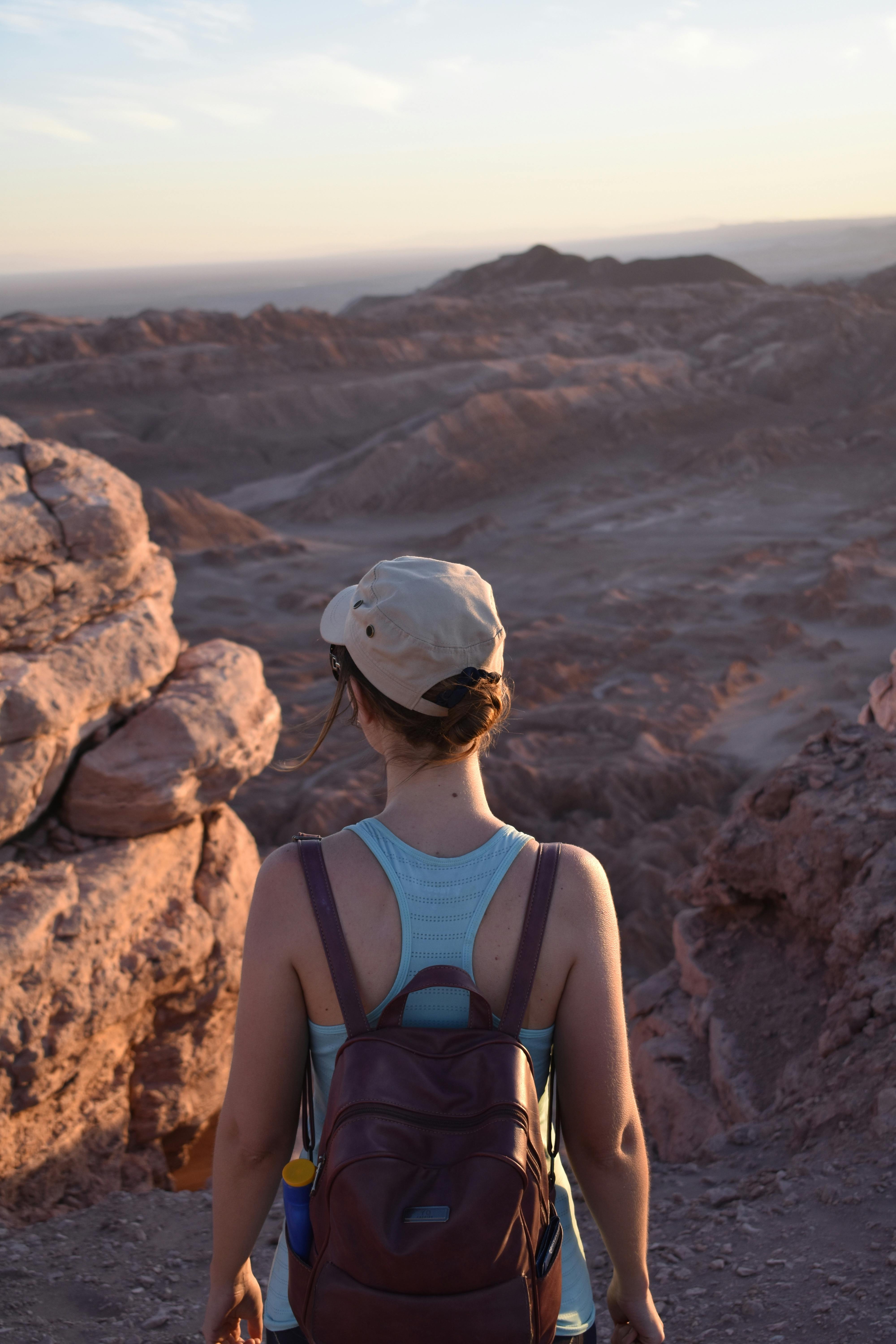 日落时分，一个女人在岩石嶙峋的干旱山区徒步，探索大自然的美丽
