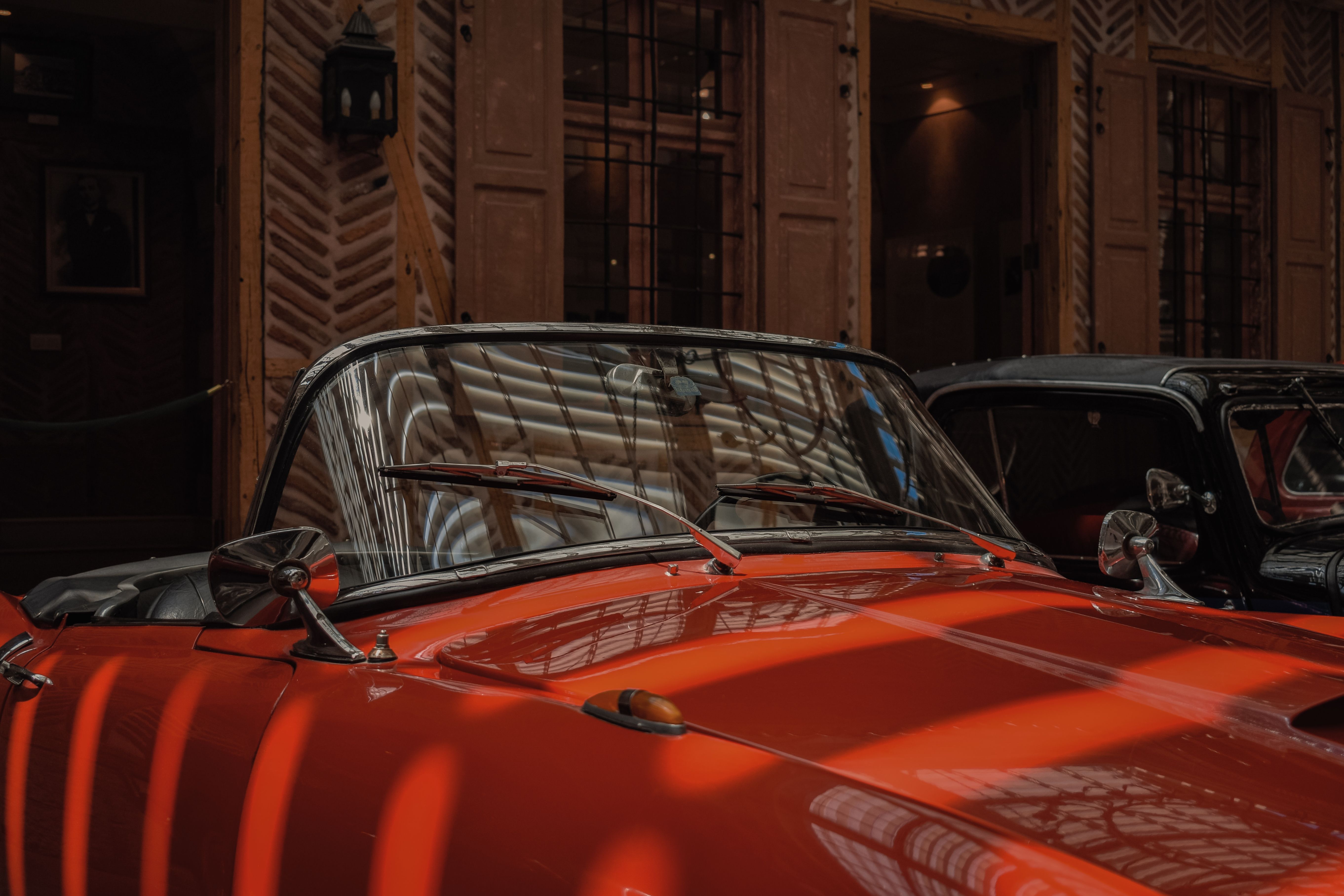 A classic red convertible car shown indoors under soft lighting.