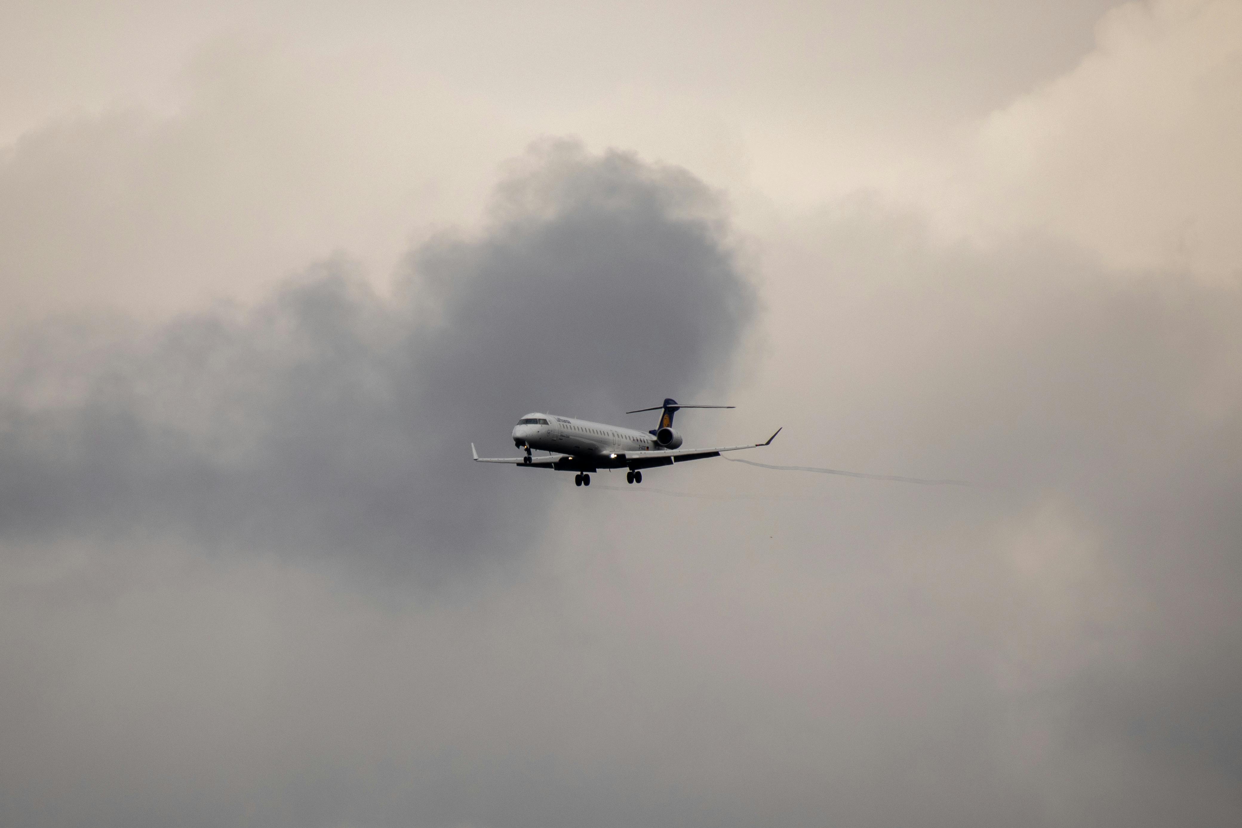 A commercial airplane navigating through dark cloudy skies, showcasing aerial travel and atmospheric conditions.