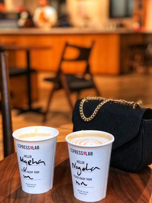 Free Close-up of Two Coffees in Paper Cups and a Bag Standing on the Table in a Cafe Stock Photo