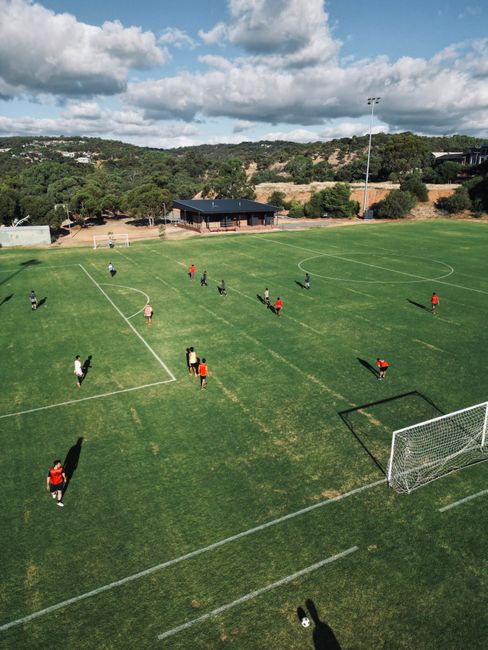 Players spread across a community oval seen from above.