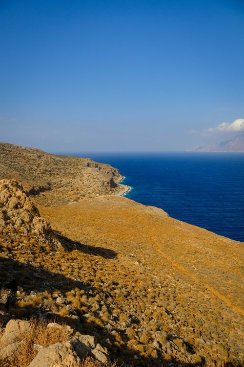 Free Beautiful landscape of a rocky coastline with vibrant blue ocean and clear sky. Stock Photo