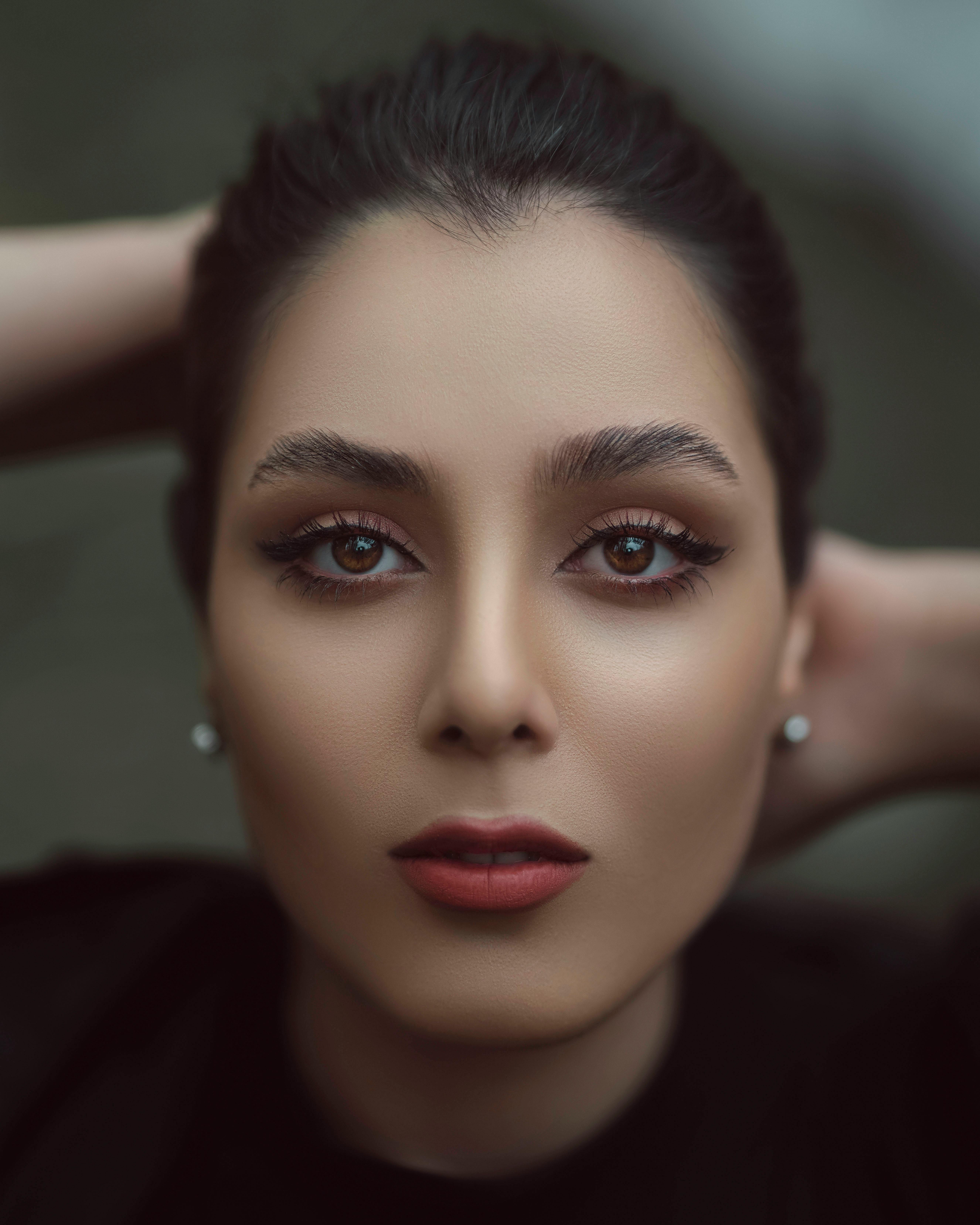 Close-up portrait of a young woman with brown eyes and elegant makeup, showcasing her beauty.