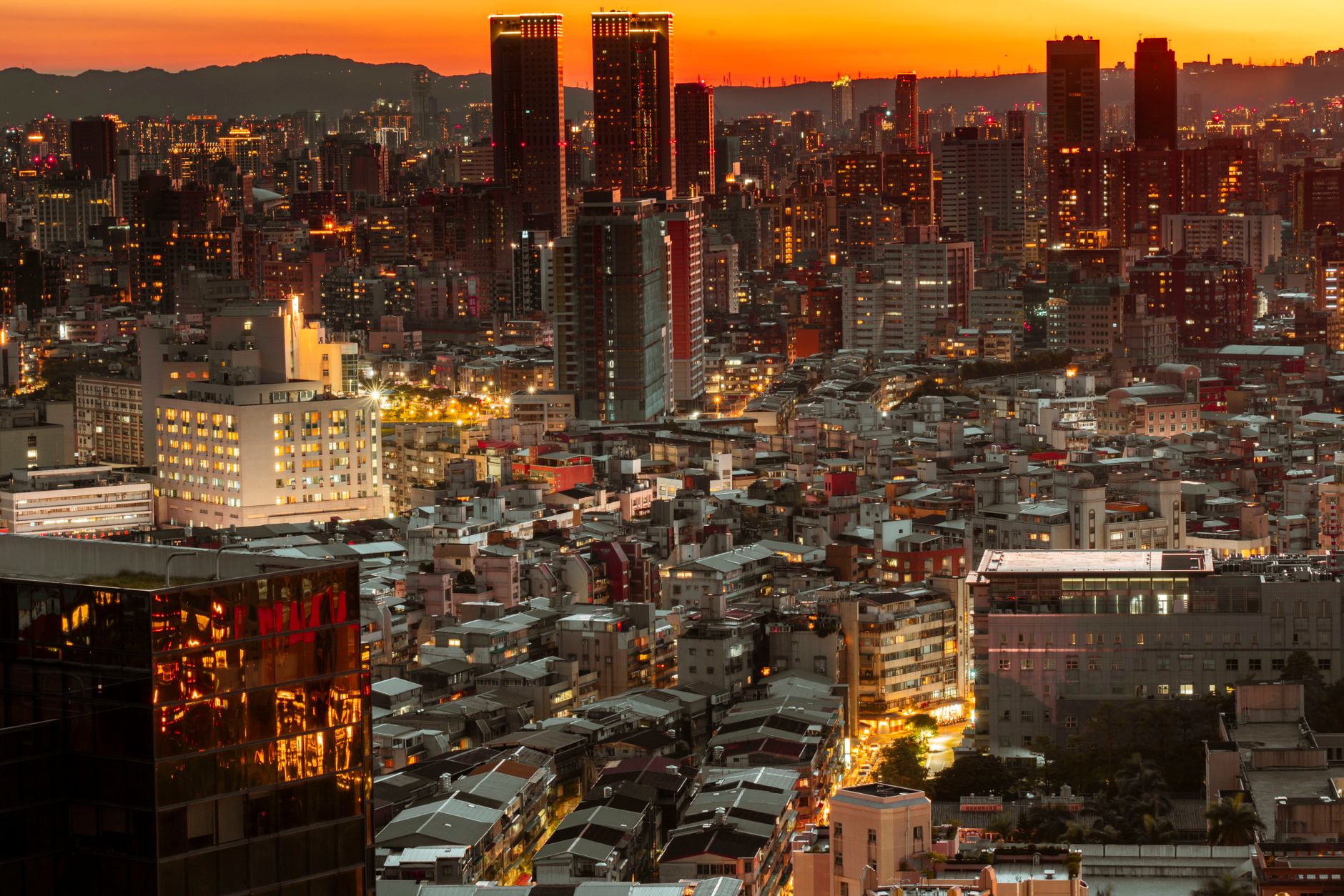Illuminated city skyline with skyscrapers glowing at sunset, capturing urban beauty.