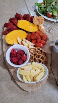 A vibrant selection of fresh fruits and snacks arranged artfully on a wooden board.