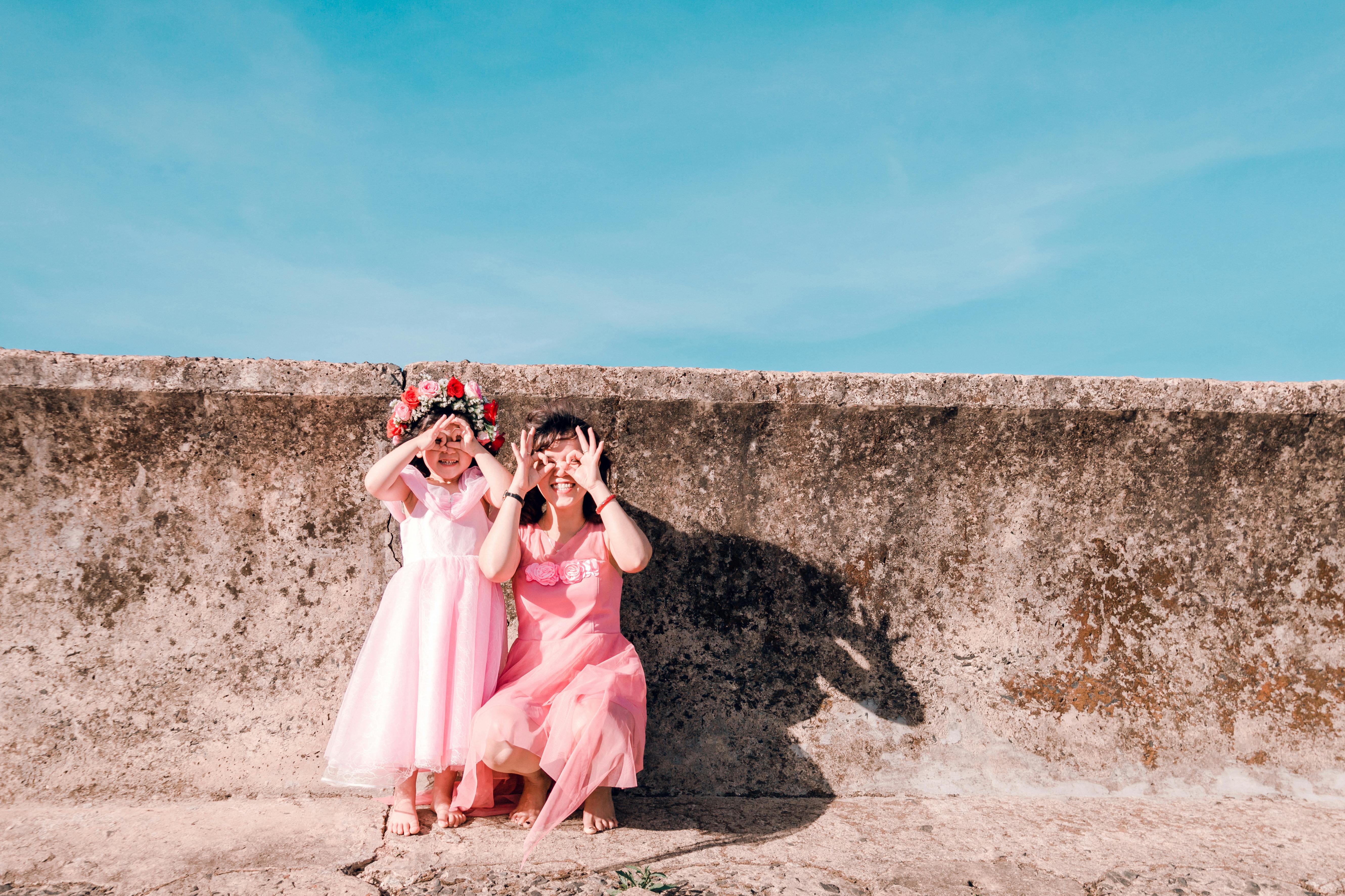 Tow Girls Sitting Beside Concrete Wall