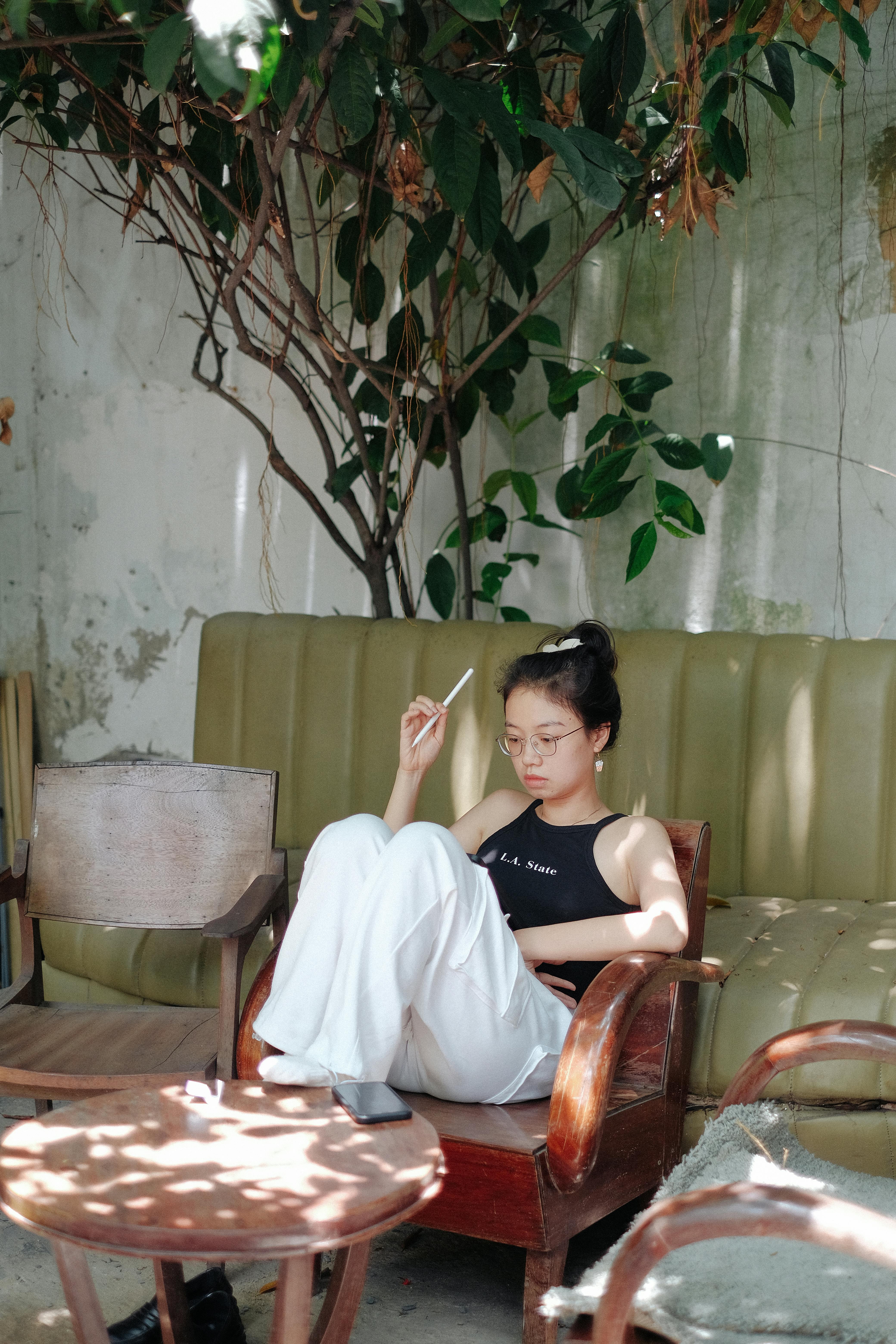 Young woman sitting in outdoor patio, enjoying relaxation and sunlight.
