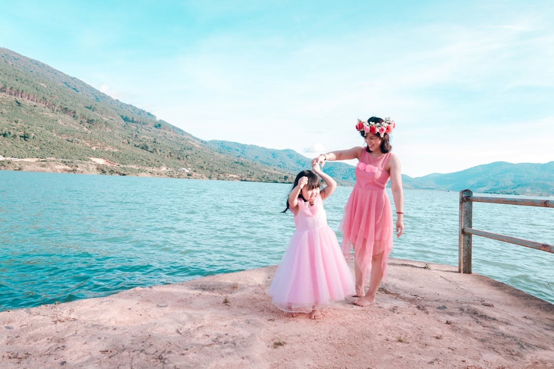 Woman and Child Wearing Pink Gowns Near Sea