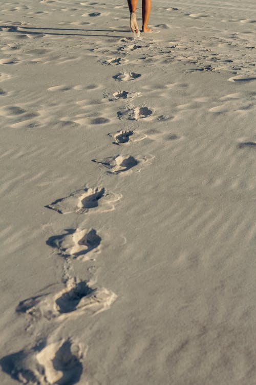 Person Walking Barefoot and Leaving Footsteps in the Sand 