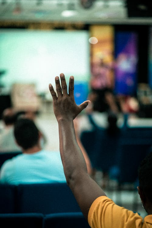 Man Sitting in the Audience and Raising his Hand 