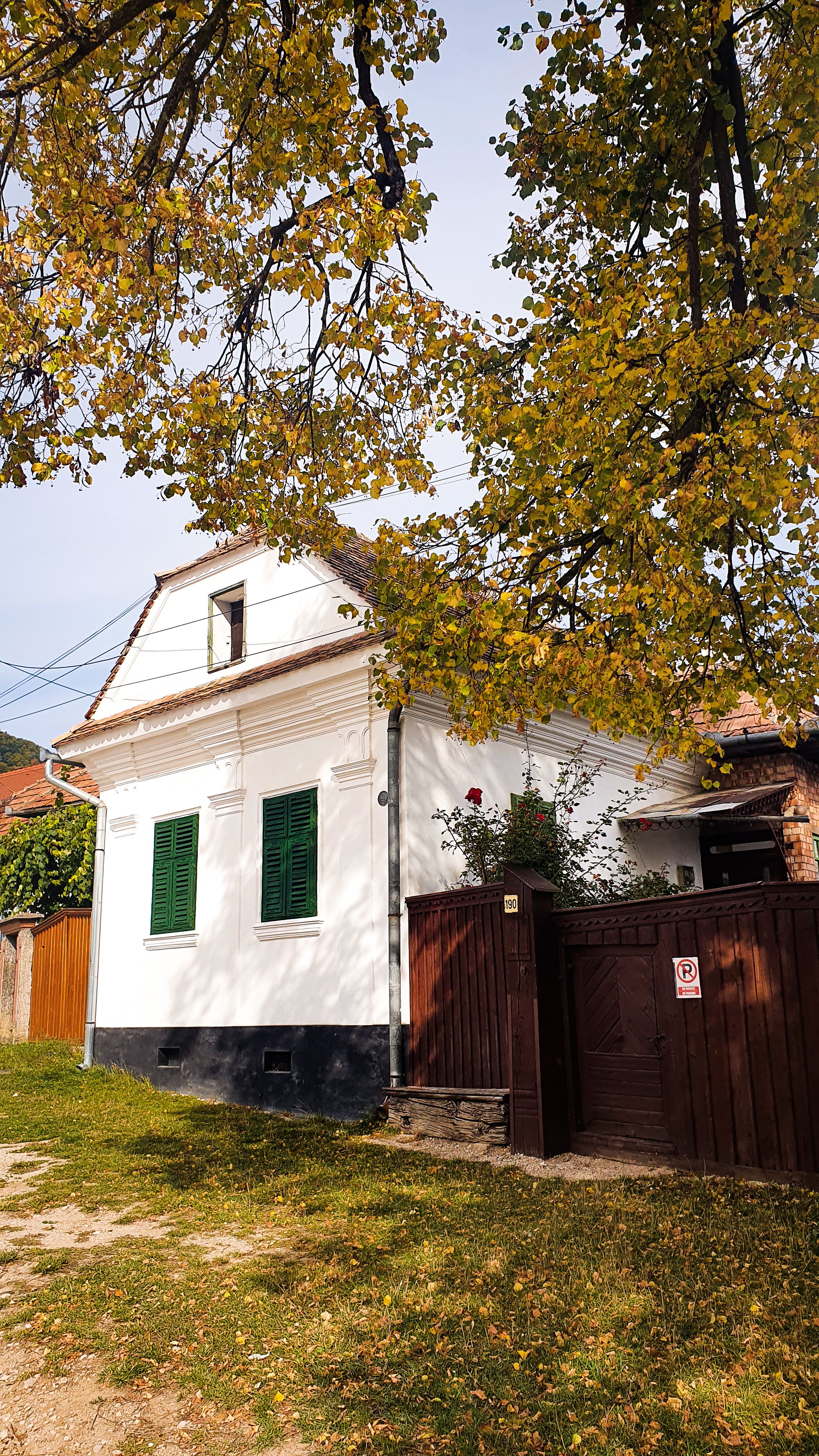 Quaint white house with green shutters in a picturesque rural setting in Rimetea, Romania.