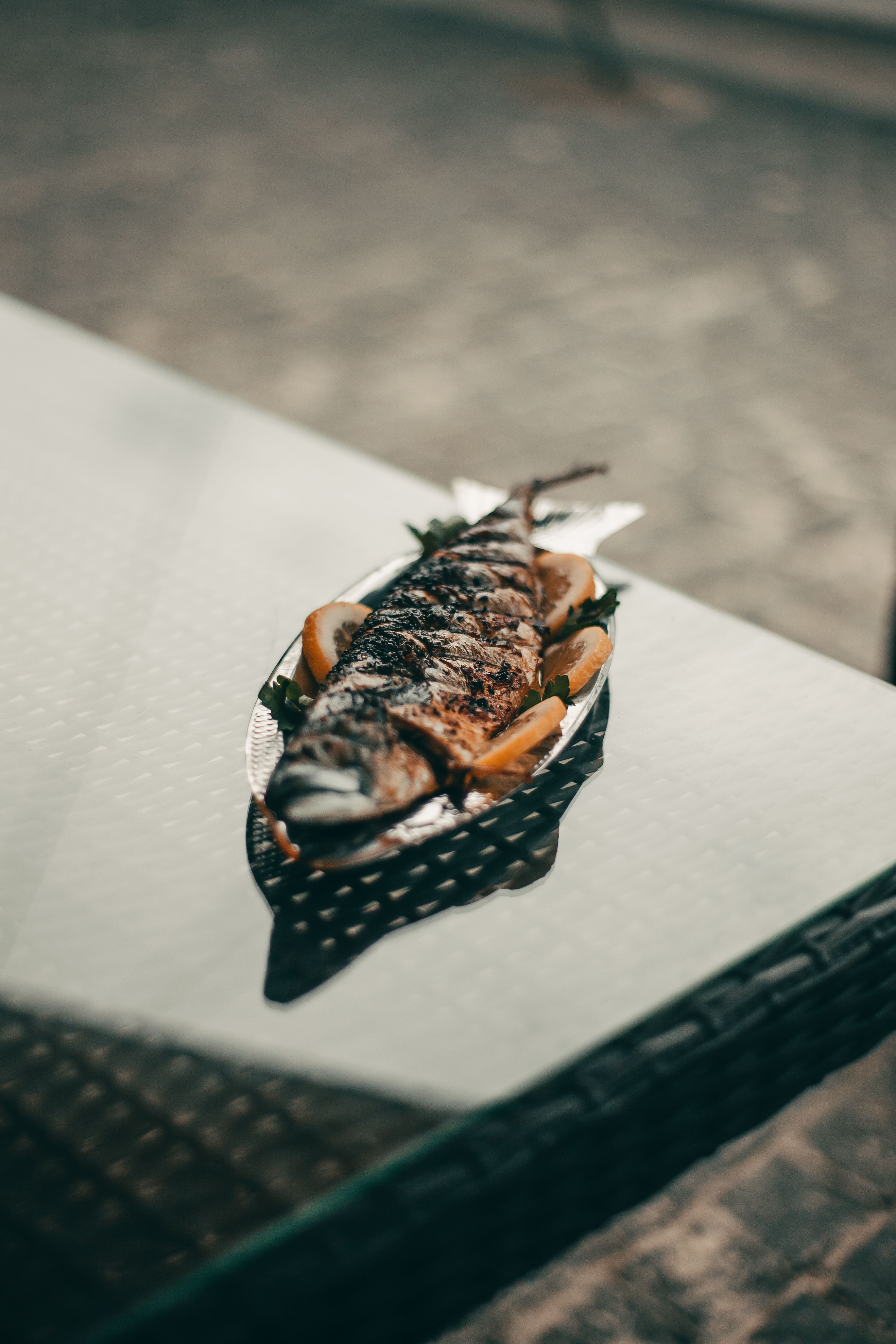 Grilled fish served with lemon slices on a plate, perfect for seafood lovers.