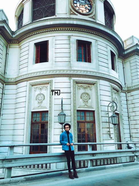 A person standing outside a historic building with ornate architecture and large windows.