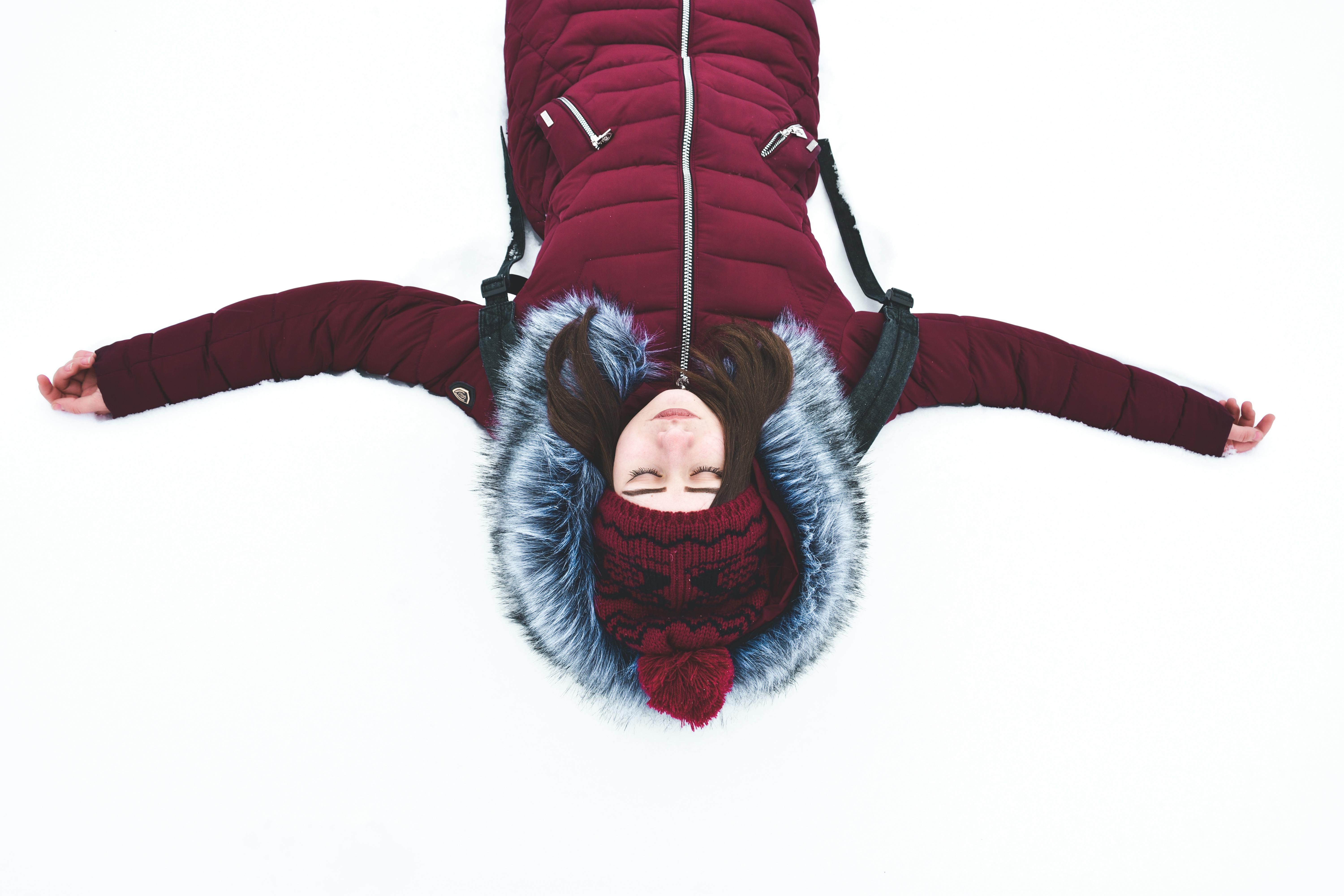 woman lying on snow with arms wide open