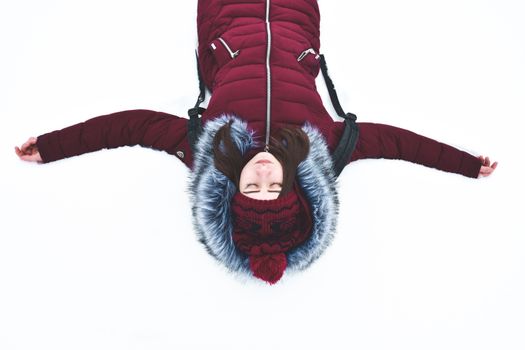 一位身着红色冬衣的女子张开双臂，躺在雪地上，完美捕捉了冬日的宁静