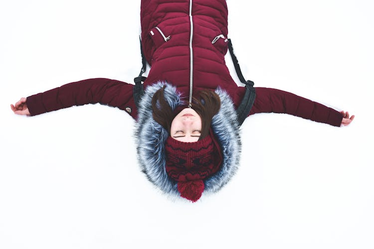 Woman Lying On Snow With Arms Wide Open