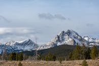 乌云密布的天空下，白雪覆盖的山峰和森林呈现出壮丽的景色