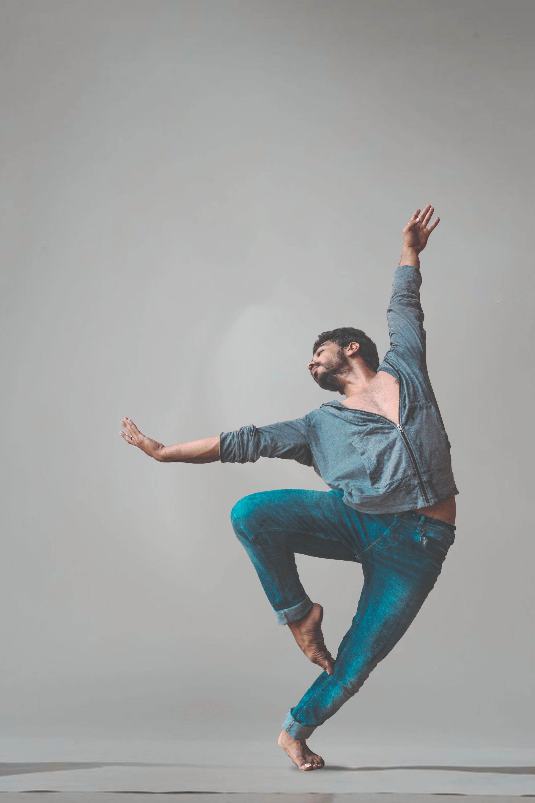Bailarín en un gesto de giro con un brazo en alto, sobre fondo claro