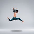 一位男舞者在工作室里完成了一次有力的飞跃，展现了他的敏捷身手