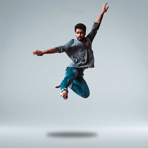 Free Man Jumping While Raising His Both Arms Stock Photo