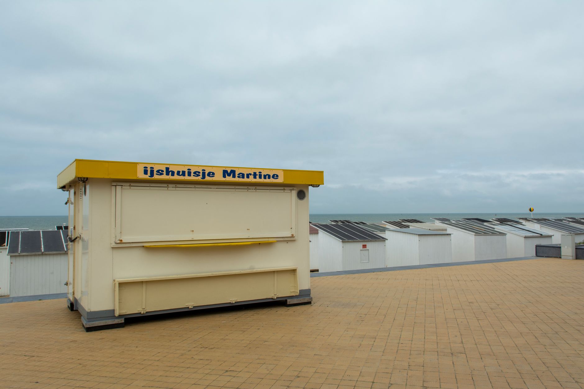 Ice cream stand and beach huts along Oostende's scenic beachfront promenade.