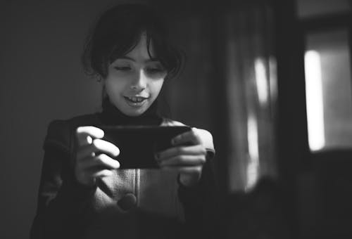 Grayscale Photography of Girl Using Smartphone