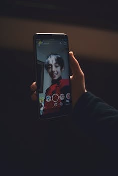 夜晚，一个人用智能手机拍照的特写，画面中可见手机屏幕及其反光