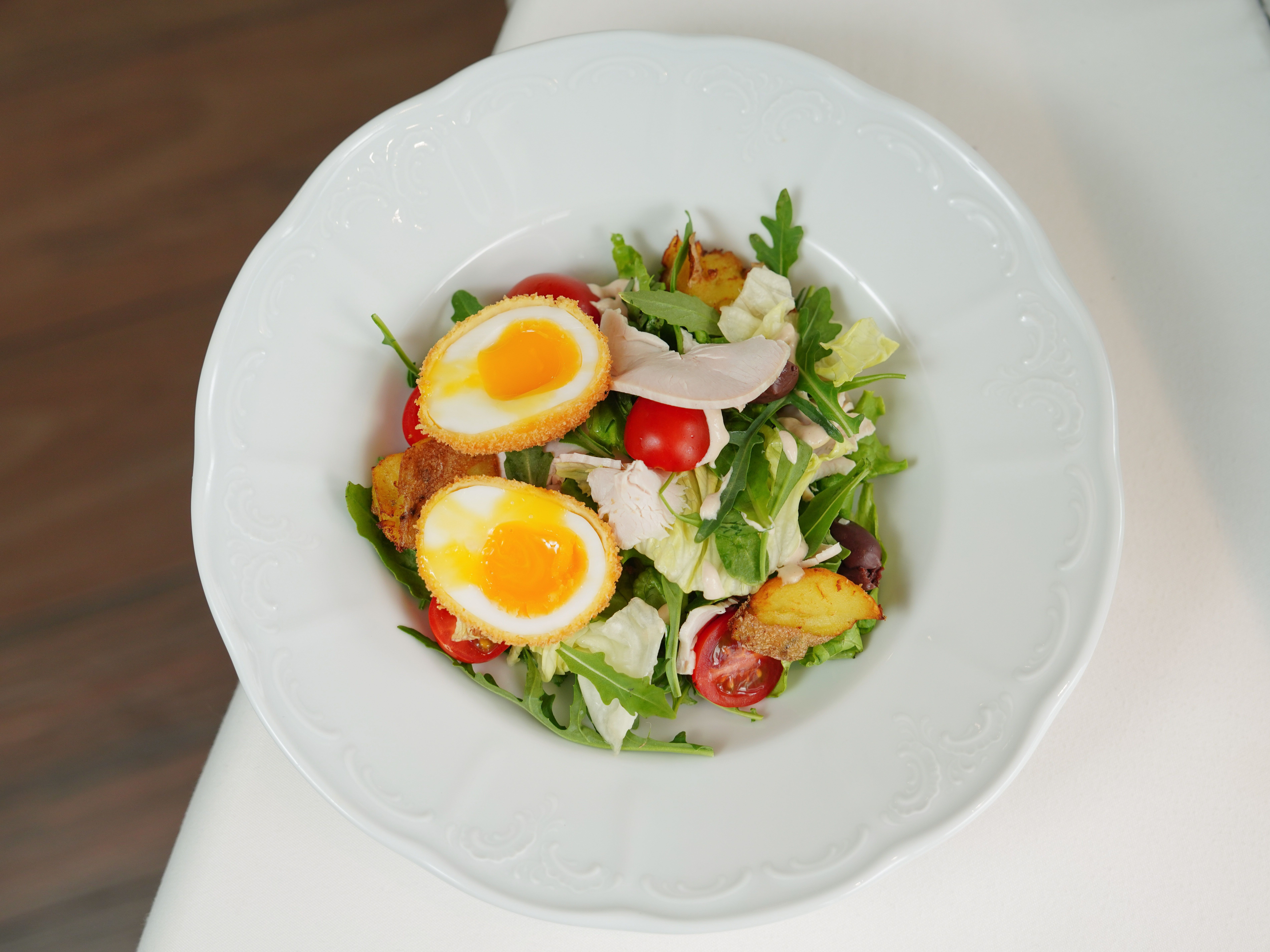 Delicious mixed salad with soft boiled eggs, tomatoes, and greens. Perfect for a fresh lunch.