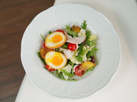 Delicious mixed salad with soft boiled eggs, tomatoes, and greens. Perfect for a fresh lunch.