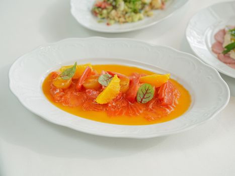 A gourmet salmon dish with oranges and sauce on a white plate, perfect for fine dining.