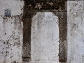 A weathered stone wall with an Arco del Triunfo street sign in a historic city.