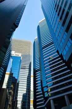 Vertical shot of modern skyscrapers in downtown Hong Kong with reflective glass facades.