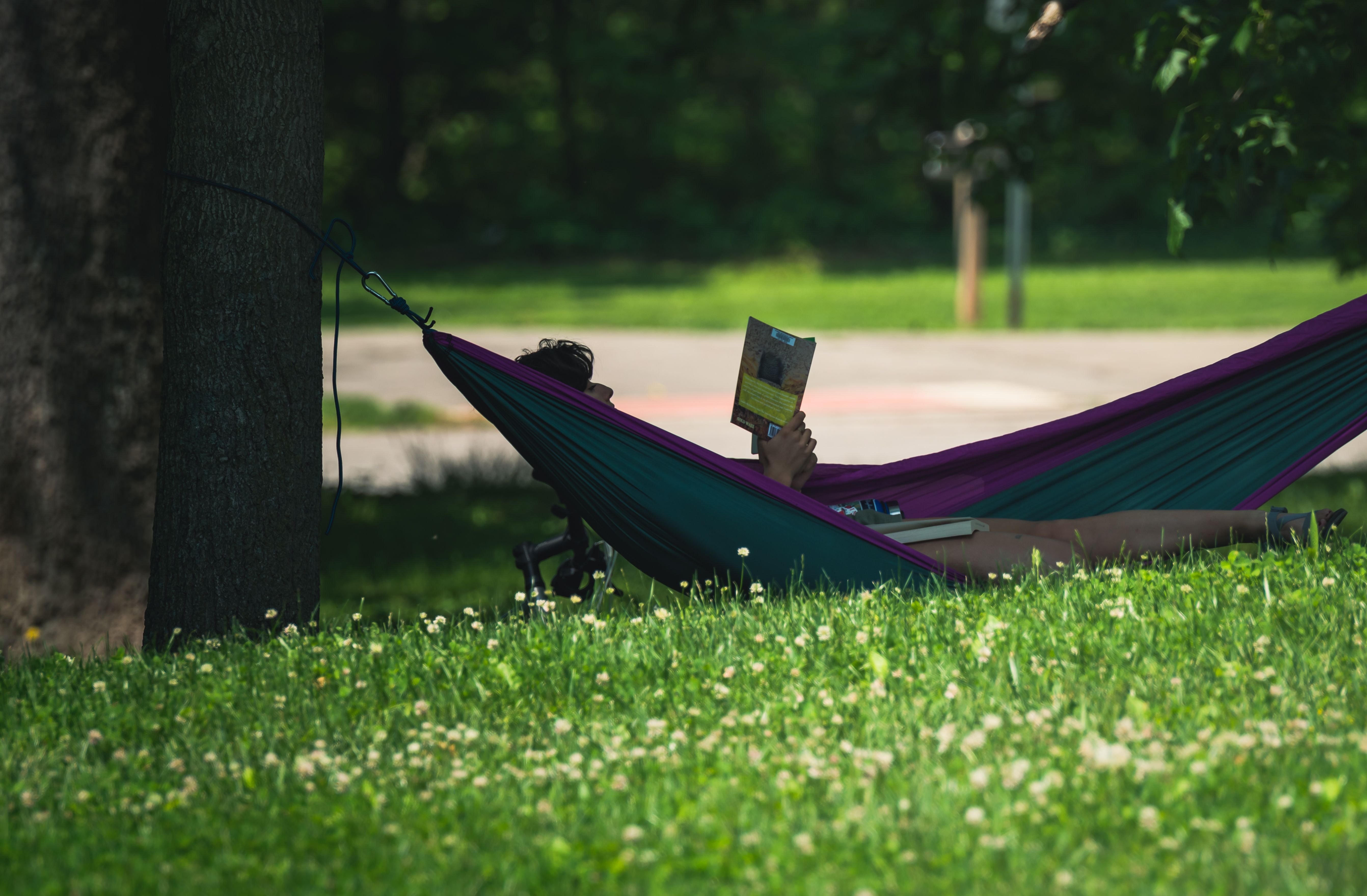 Person reading a physical book in a hammock